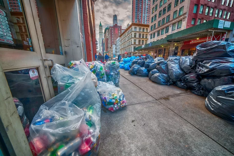 Black and blue bags of trash piled on a New York City sidewalk
